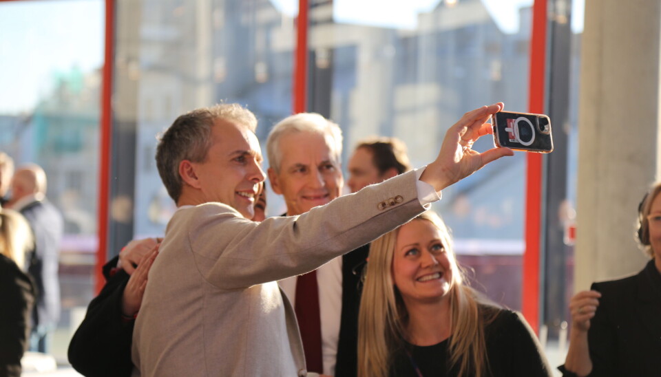 En smilende statsminister tar selfie med konferansedeltakere.